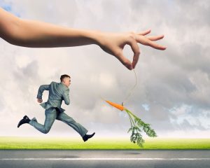 Motivated businessman running after carrot