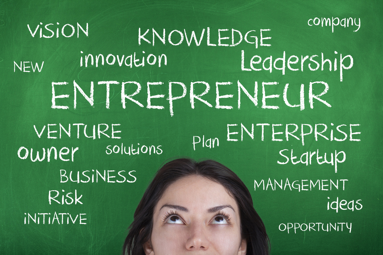 Woman entrepreneur in front of a chalkboard, thinking about leadership.