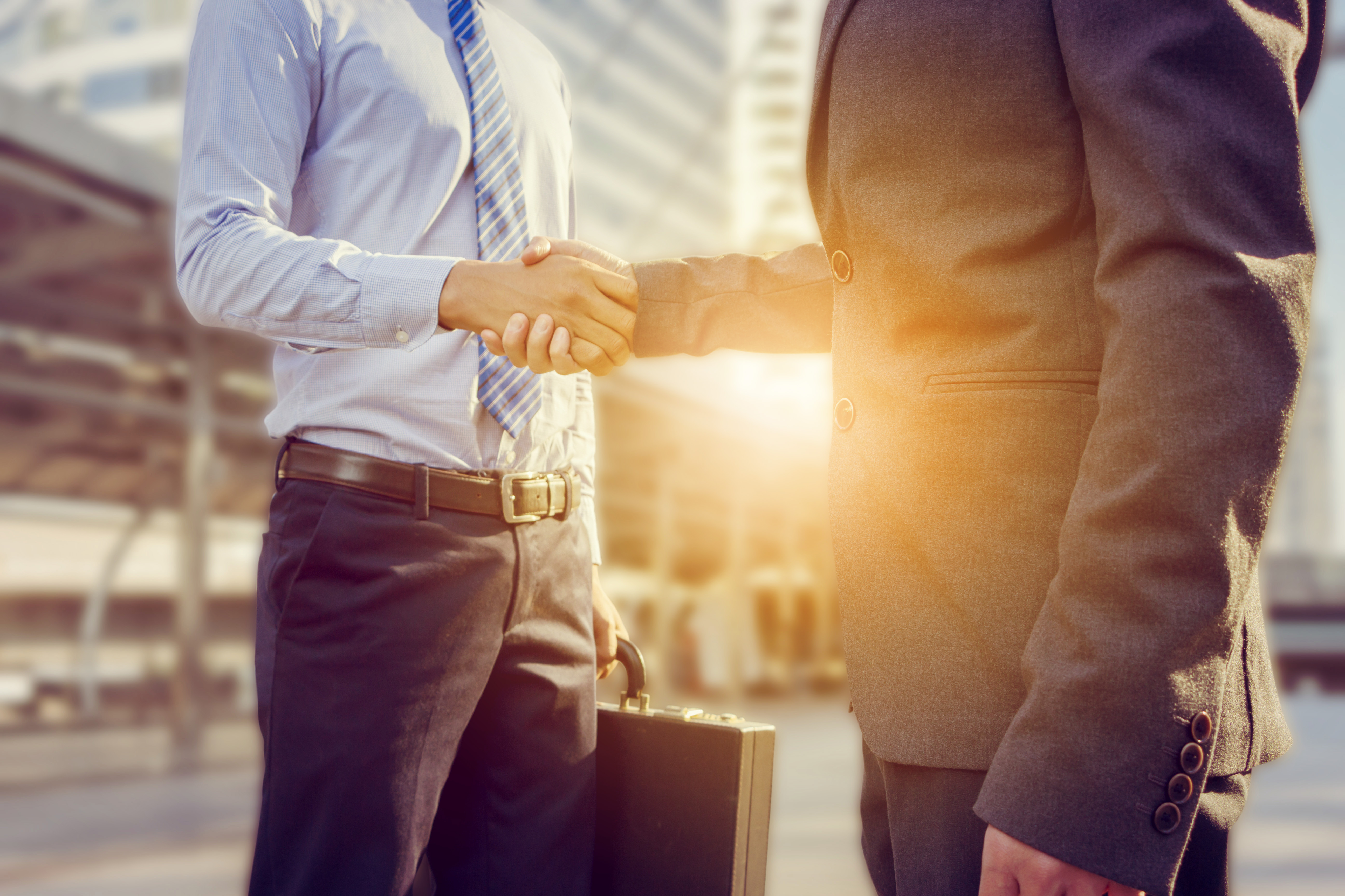 Two sales people shake hands on the street.