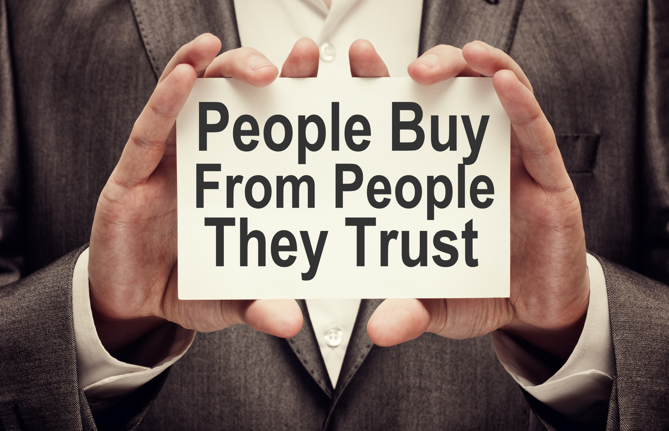 People Buy From People They Trust. Businessman holding a card with a message text written on it