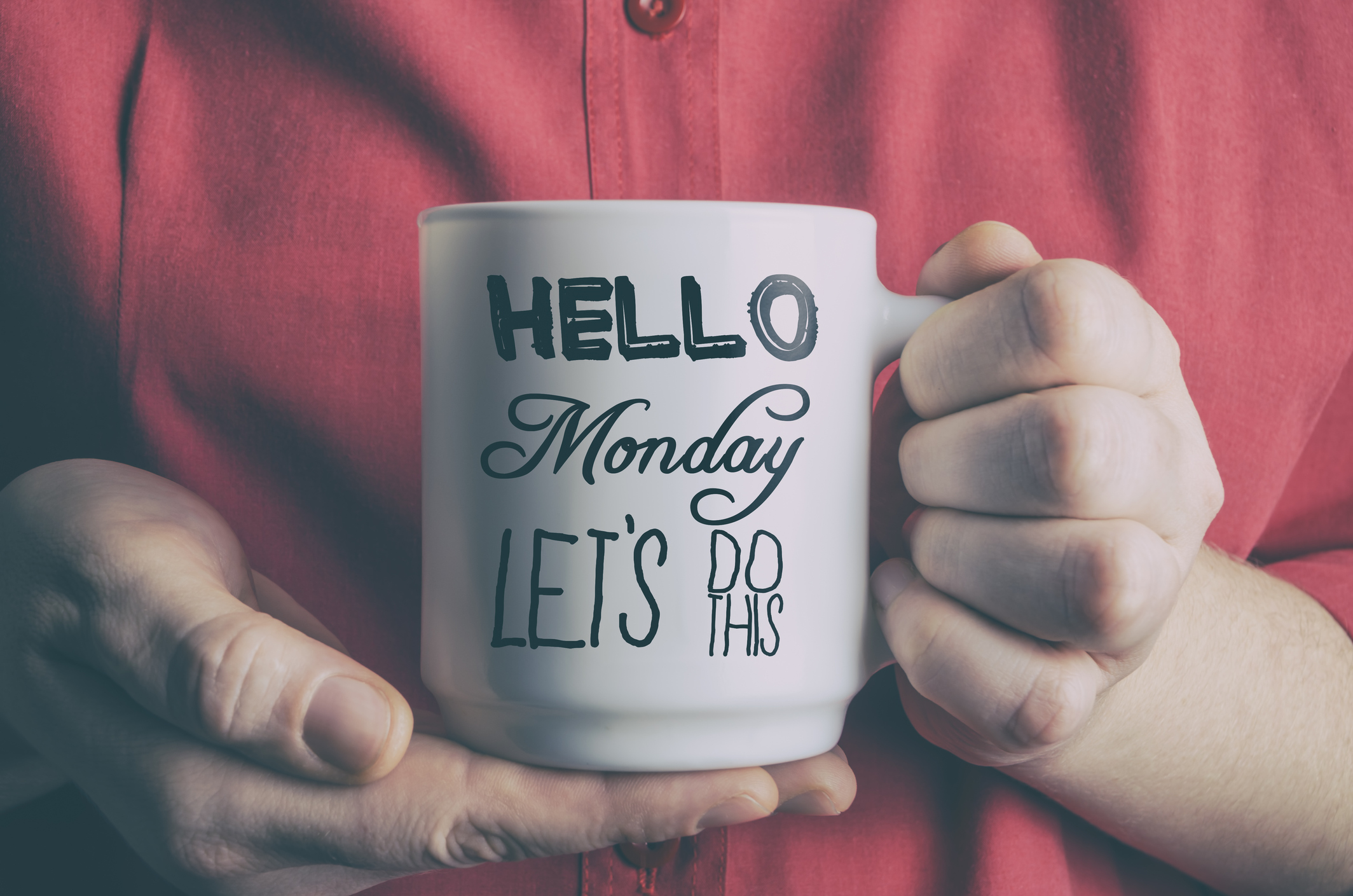 Image of a person holding a cup in his/her hands that says "Hello Monday Let's Do This!"