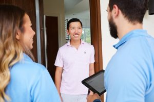 Door to door residential sales reps pitch a customer at the door to their house.