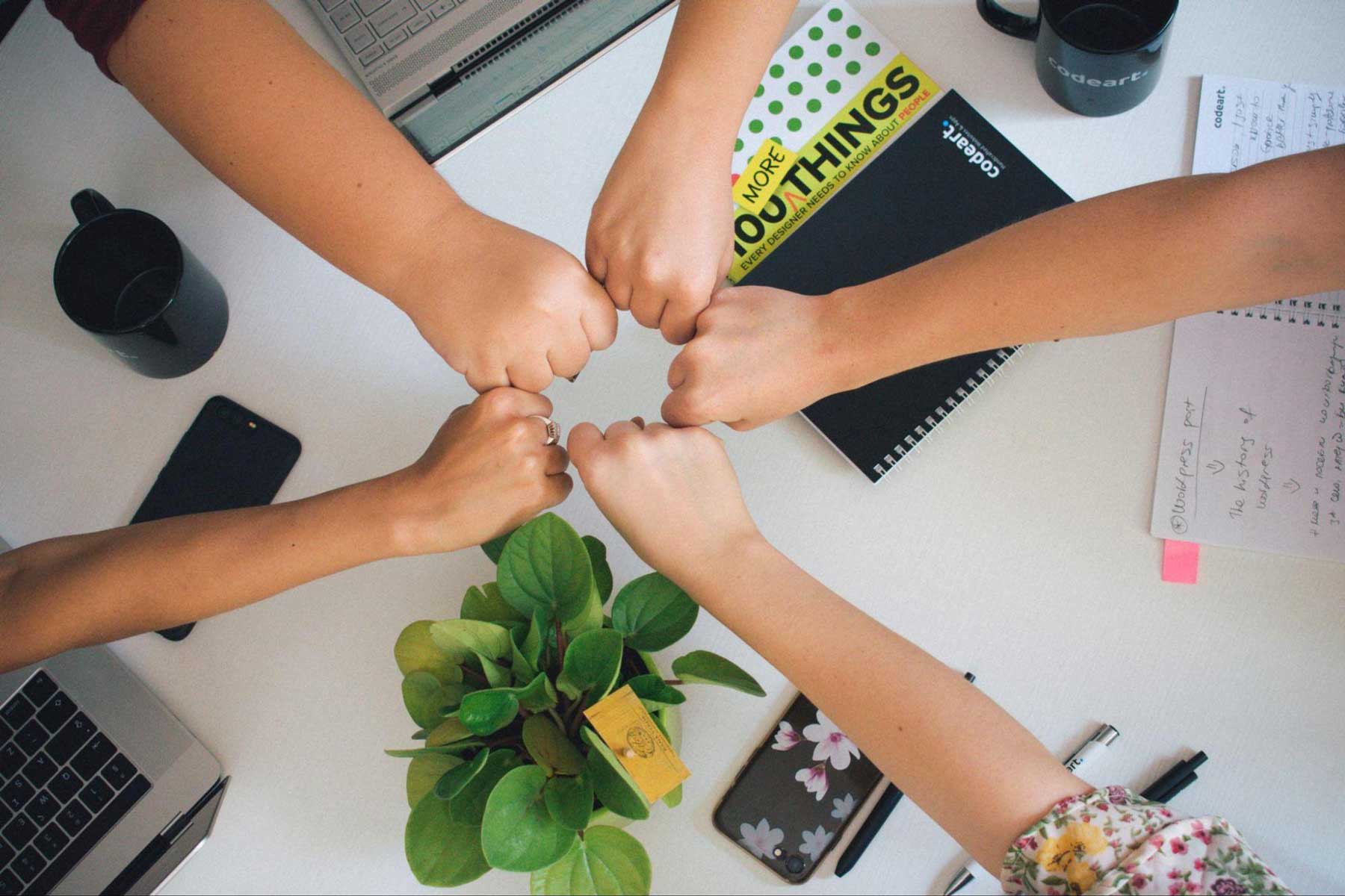 Group of coworkers fist bumping over their desks